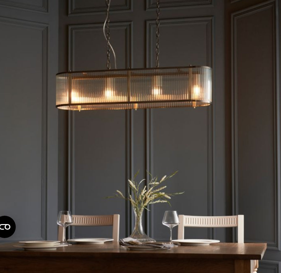 Chandelier with brass frame and ribbed, clear glass panels hanging from a chain in a dining room