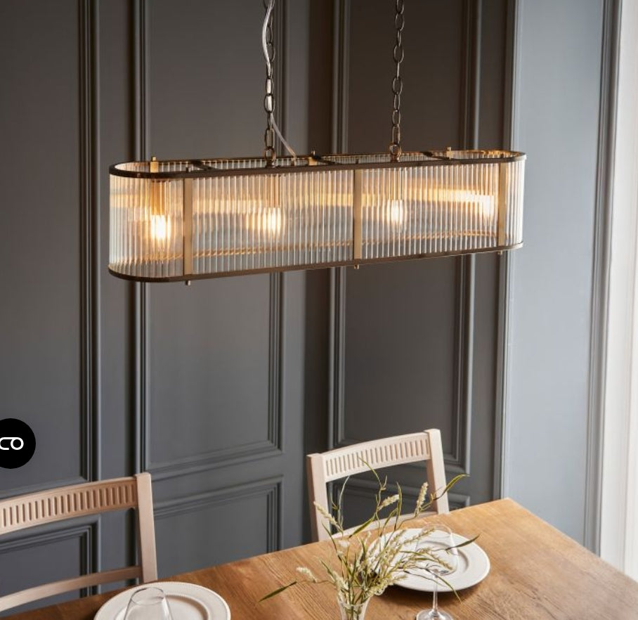 Chandelier with brass frame and ribbed, clear glass panels hanging from a chain over a dining table