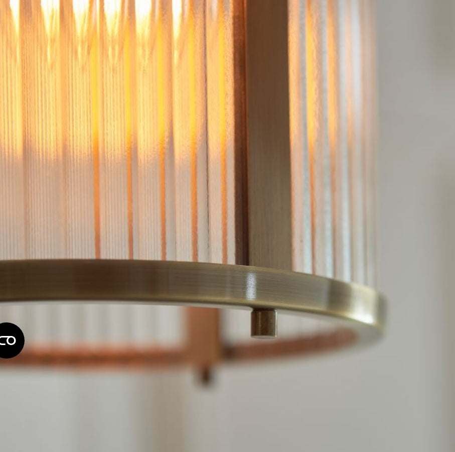 Pendant brass metal light with ribbed glass shade hung on a chain, close up