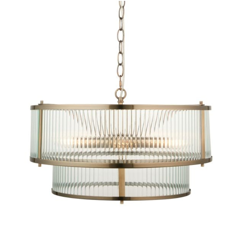 A two-tier drum pendant chandelier light with a brushed brass frame and clear ribbed glass panels, suspended from a matching chain against a white background, available from Albury House Interiors.