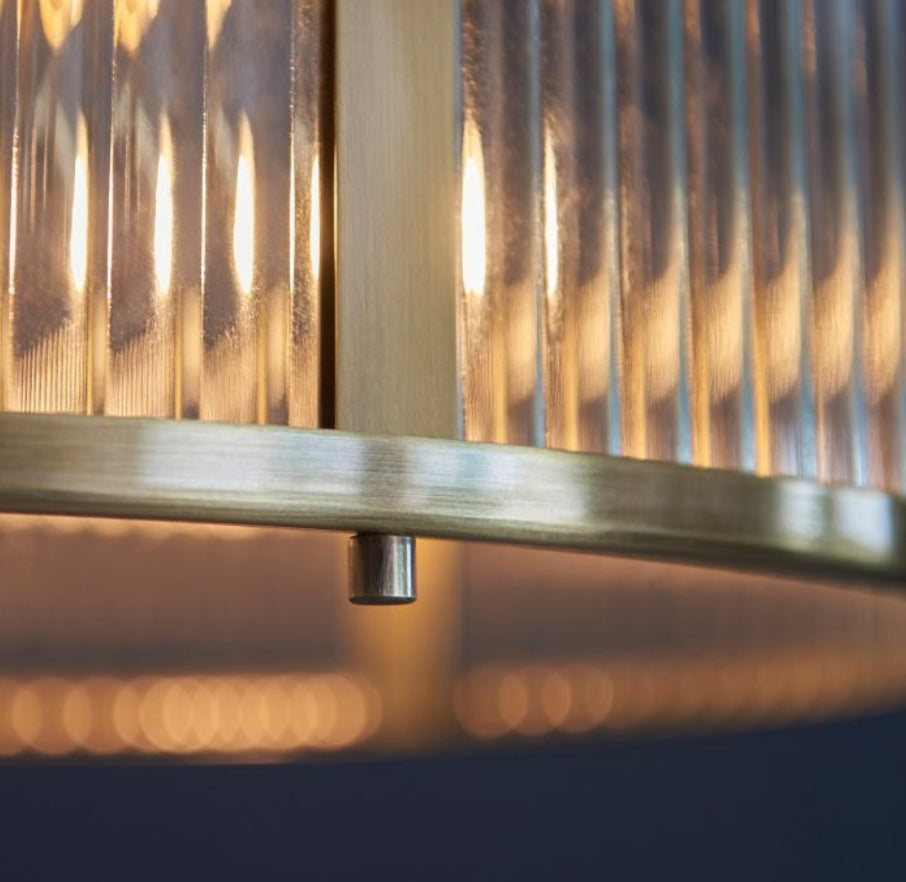 Chandelier with brass finish and clear, ribbed, glass shade hung on a metal chain close up