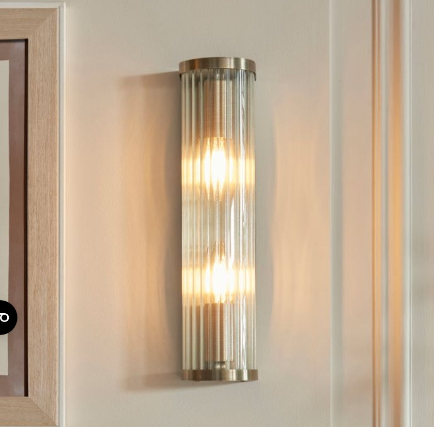 Tall cylindrical wall light fixture with ribbed glass and brass fixtures on a painted wall. Available to purchase from Albury House Interiors. 