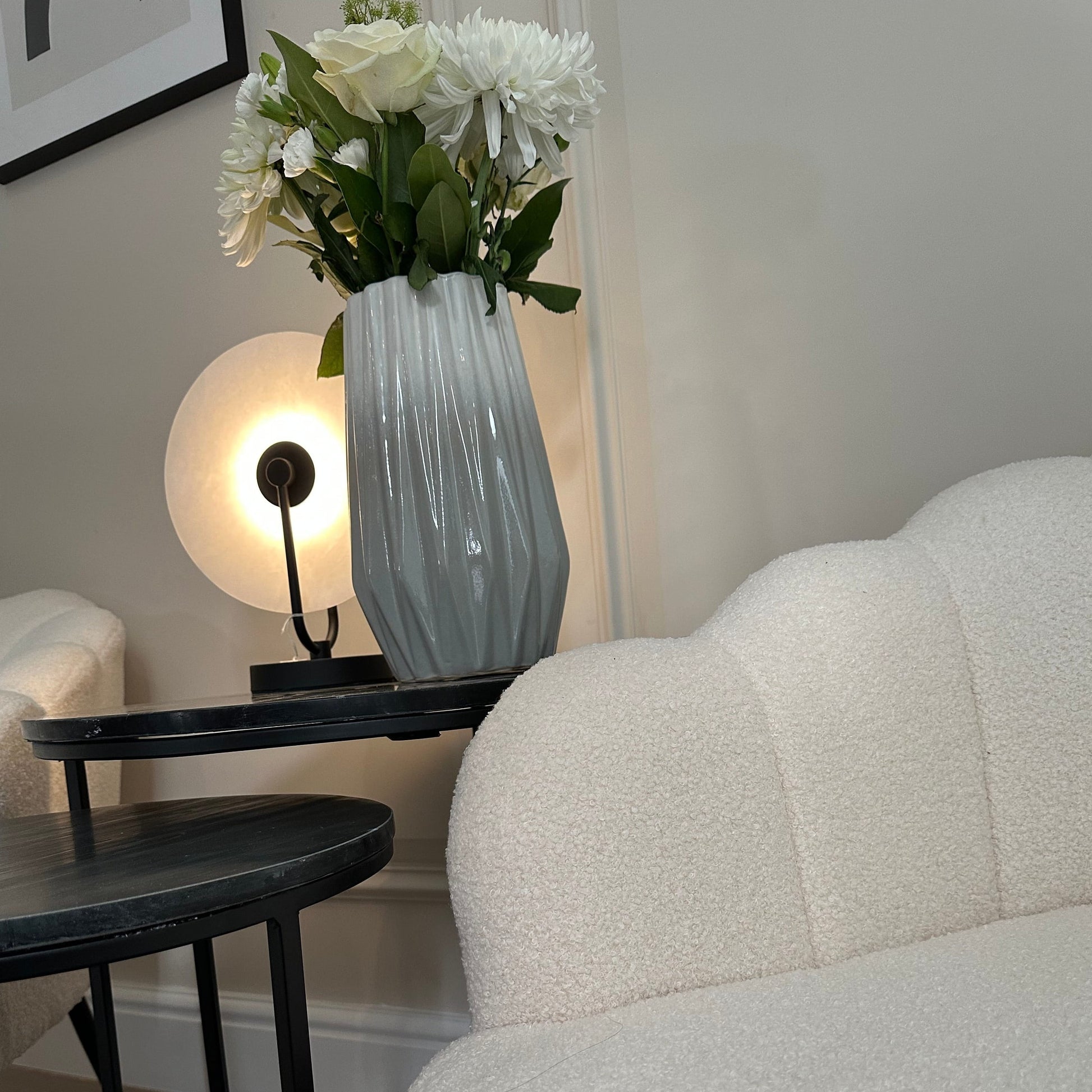 White marble quartz disc table lamp with black base and accents, with ceramic abstract dipped vase and white boucle shell shaped chair at Albury House Interiors Essex