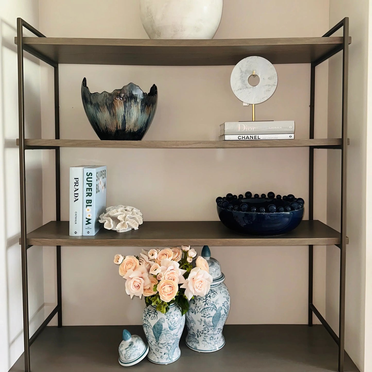 Senegal decorative lidded ginger jars in white and turquoise blue, with floral patterns and birds. Displayed on a bespoke shelving unit with designer coffee table books, marble discs on stands, and decorative bowls. Available to purchase from Albury House Interiors, home decor in Essex, UK. 