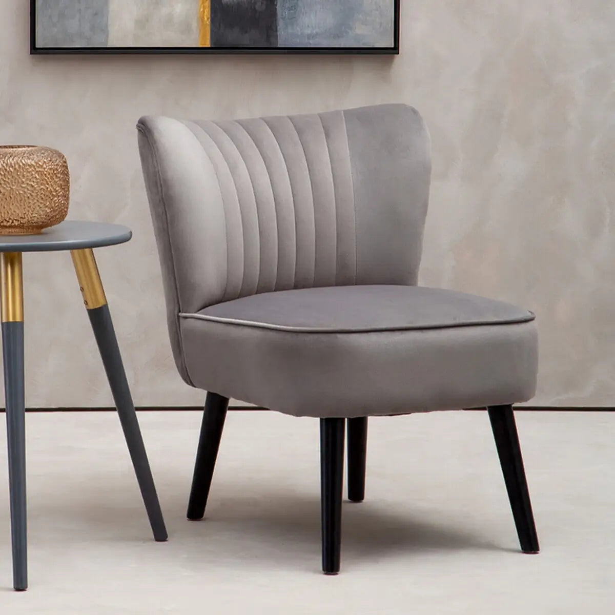 Sorrento grey velvet occasional chair with matching grey piped edges and pleated detail back, finished with black wooden legs. Available at Albury House Interiors.