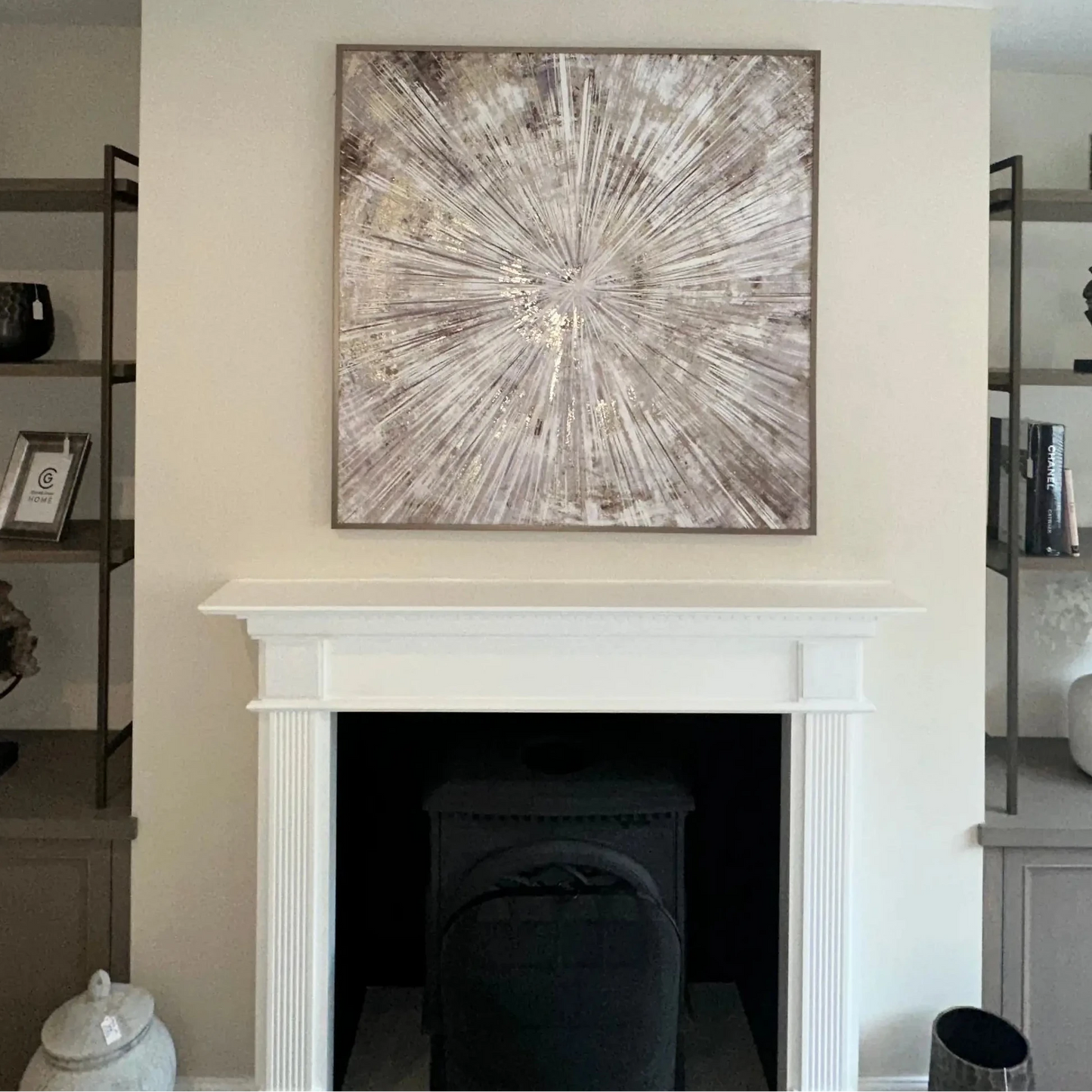 Gold framed square Starburst patterned wall art in shades of neutral, beige and gold, above a fireplace in the middle of a media wall. Available to purchase from Albury House Interiors, Essex and London.