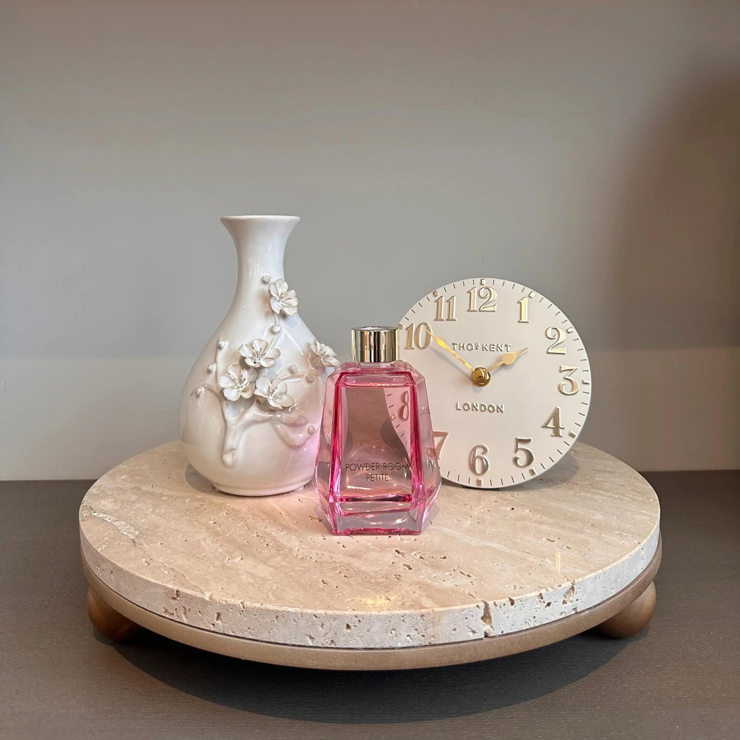 terrazzo-natural-stone-round-tray-with-wooden-ball-feet-displaying-ceramic-blossom-3d-flower-vase-and-pink-glass-powder-room-reed-diffuser-with-cream-mini-mantel-clock-at-albury-house-interiors