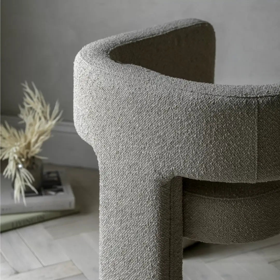 Torrent curved tub chair with three wide legs, upholstered in a beautiful neutral boucle material with matching bolster cushion. Perfect to use as dining chairs or occasional chairs in bedrooms or living rooms. Available to purchase from Albury House Interiors. 