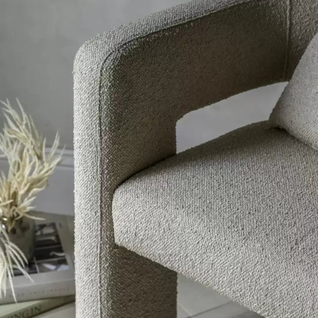 Torrent curved tub chair with three wide legs, upholstered in a beautiful neutral boucle material with matching bolster cushion. Perfect to use as dining chairs or occasional chairs in bedrooms or living rooms. Available to purchase from Albury House Interiors. 