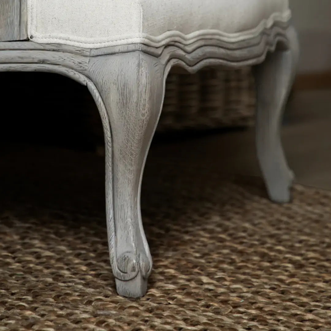 Valais solid oak frame armchair stained in a stone grey with distressed finish. Seat and back cushion upholstered in cream linen with matching armrest padding. Complete with grey rattan back. Available in oak and stone at Albury House Interiors.