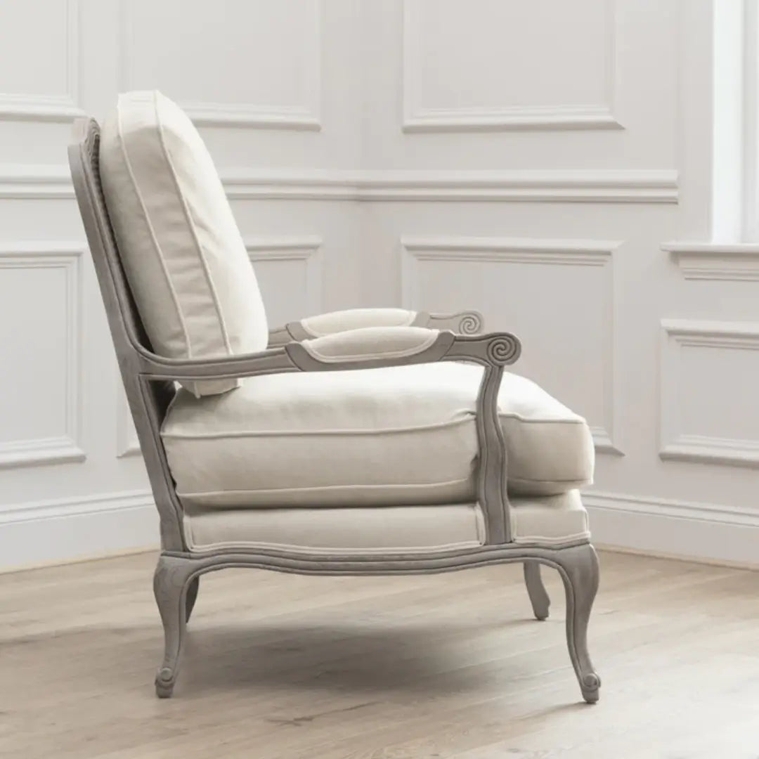 Valais solid oak frame armchair stained in a stone grey with distressed finish. Seat and back cushion upholstered in cream linen with matching armrest padding. Complete with grey rattan back. Available in oak and stone at Albury House Interiors.