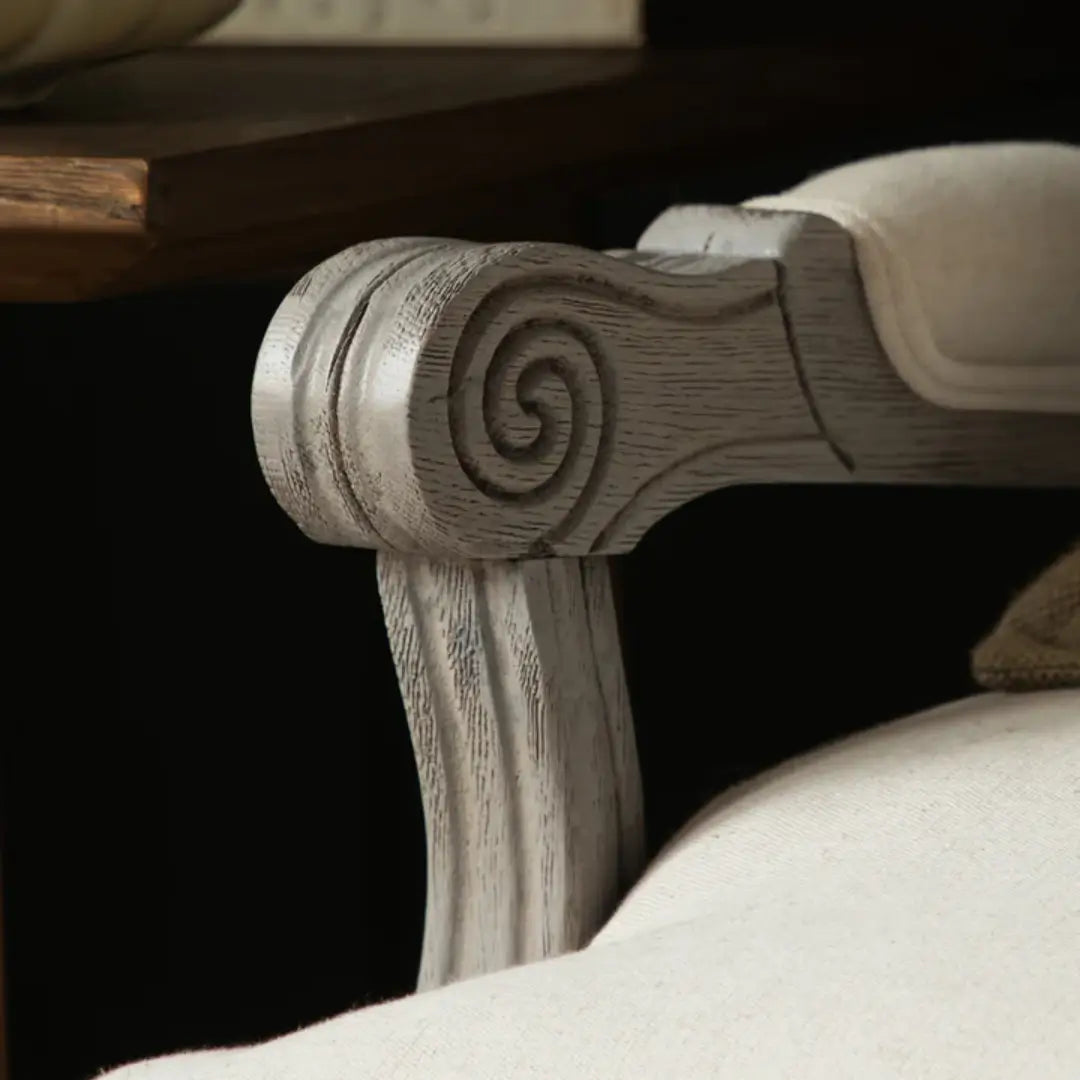 Valais solid oak frame armchair stained in a stone grey with distressed finish. Seat and back cushion upholstered in cream linen with matching armrest padding. Complete with grey rattan back. Available in oak and stone at Albury House Interiors.