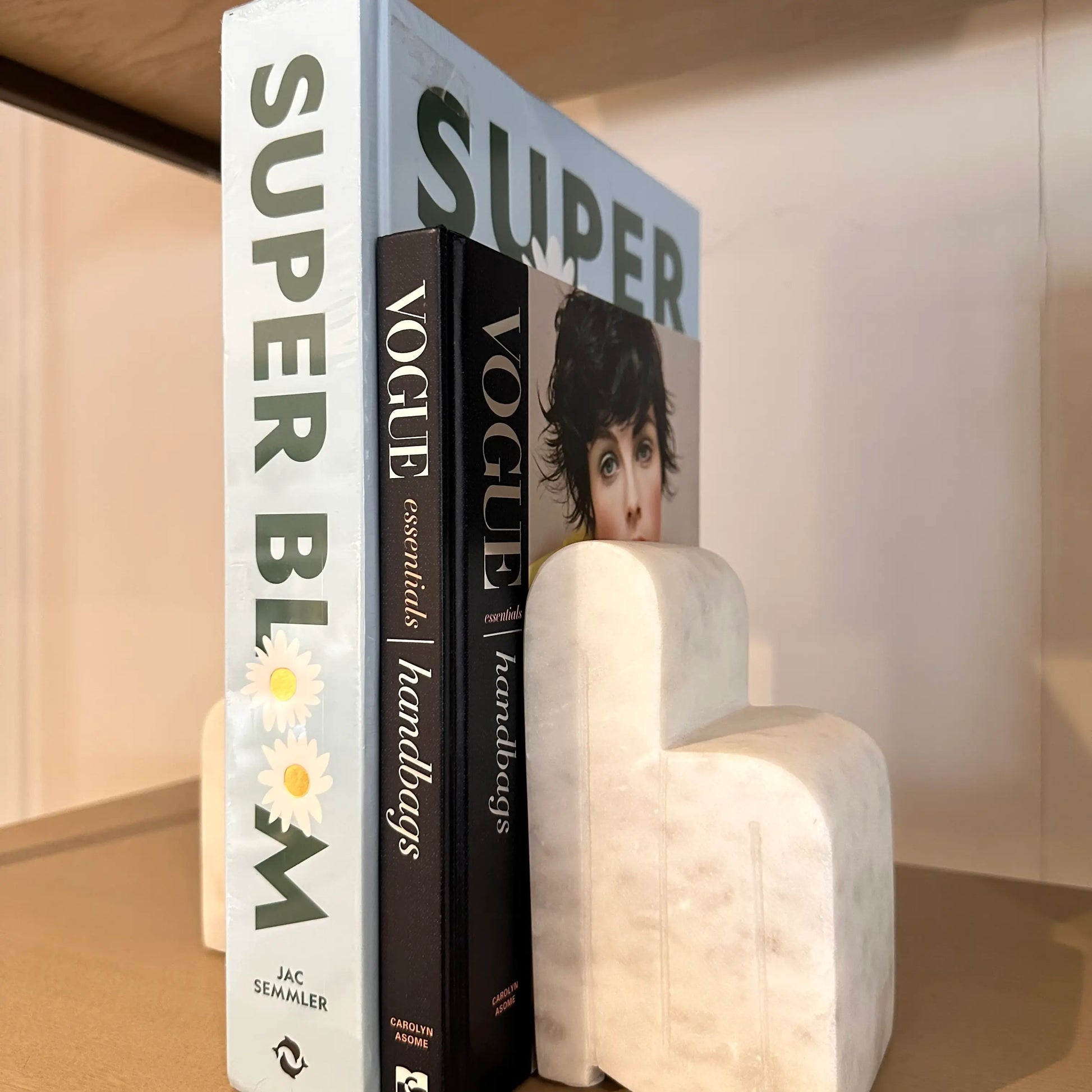 white-veined-natural-marble-arch-bookends-holding-up-baby-blue-super-bloom-and-navy-vogue-essentials-handbags-coffee-table-books-at-albury-house-interiors-essex
