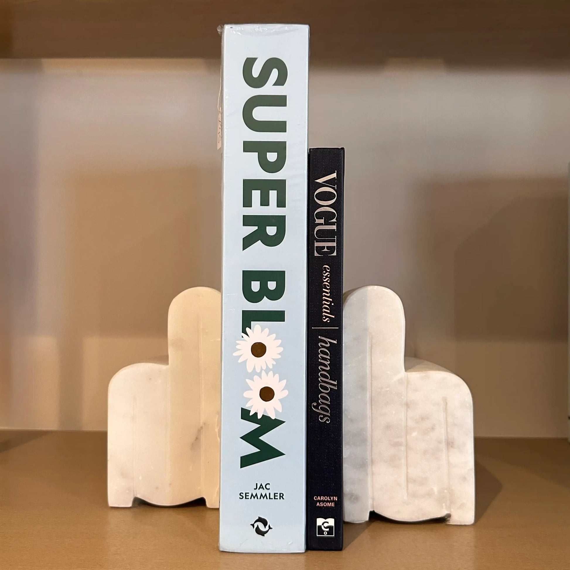 white-veined-natural-marble-arch-bookends-holding-up-baby-blue-super-bloom-and-navy-vogue-essentials-handbags-coffee-table-books-at-albury-house-interiors-essex