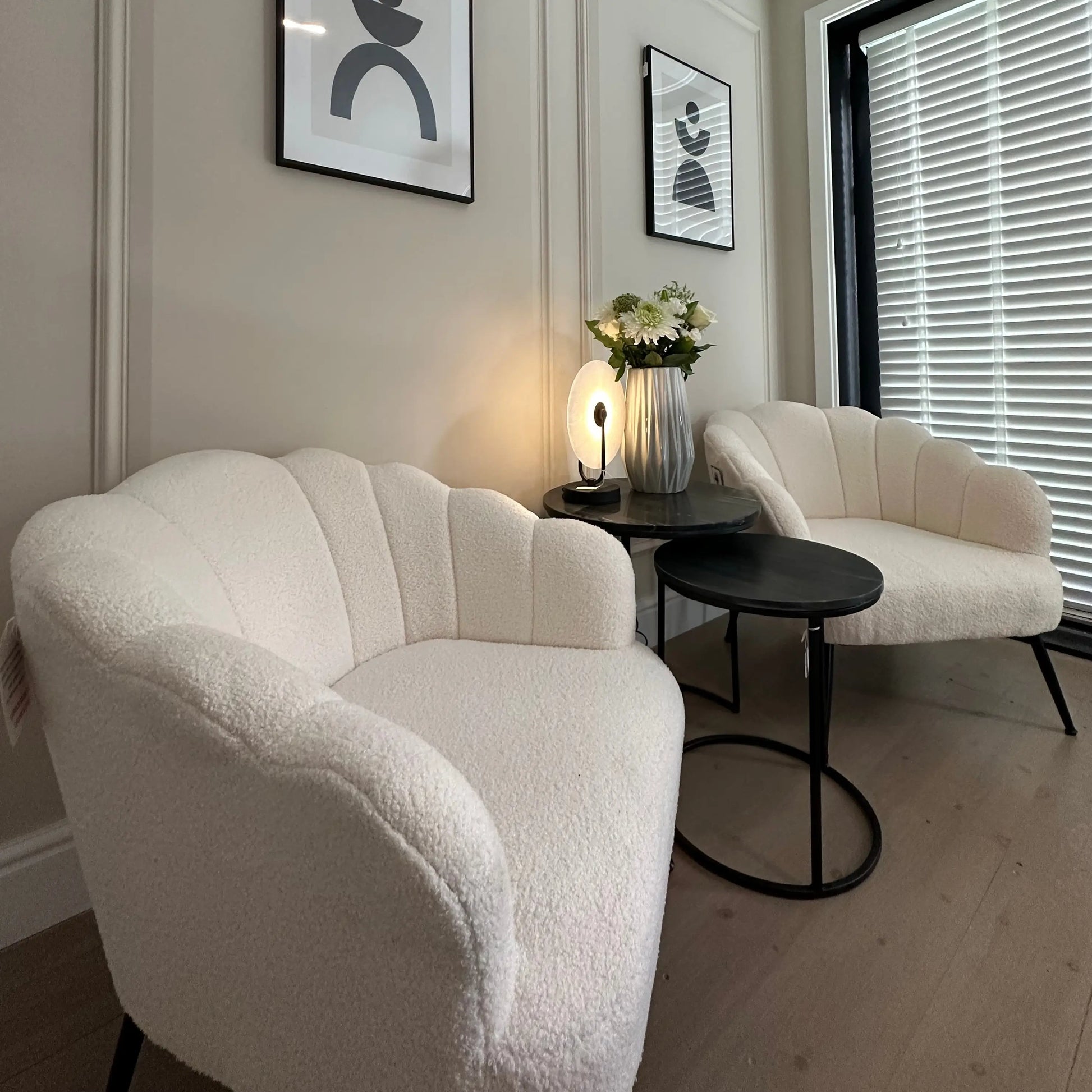 White soft boucle armchair occasion chairs in a shell shape with scalloped edges and matte black legs, paired with nesting black marble side tables and marble lamp. All items available to purchase from Albury House Interiors, Essex. 
