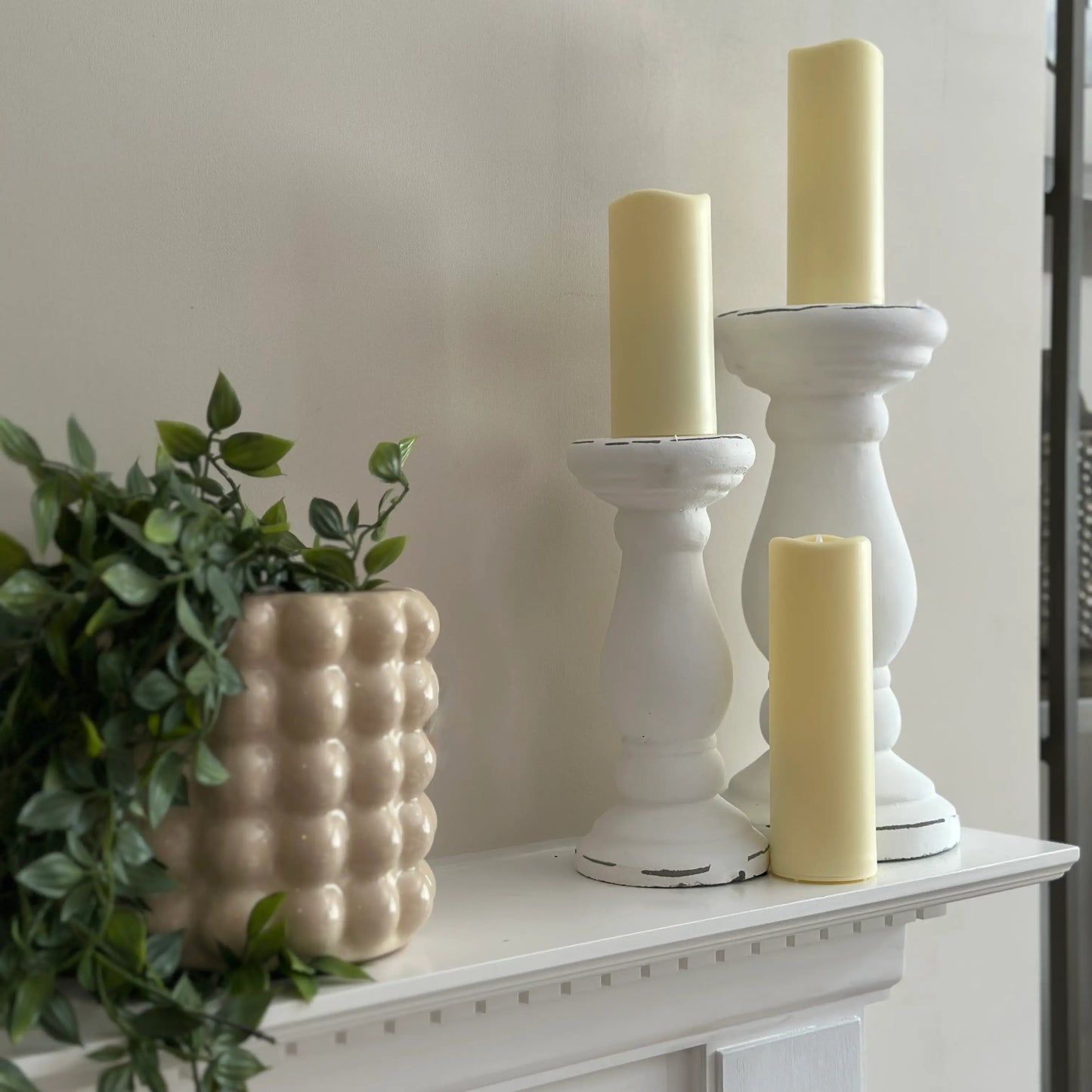 white-ceramic-pillar-candle-holders-in-sizes-small-and-large-on-white-fire-surround-mantel-with-cream-bubble-ceramic-planter-at-albury-house-interiors