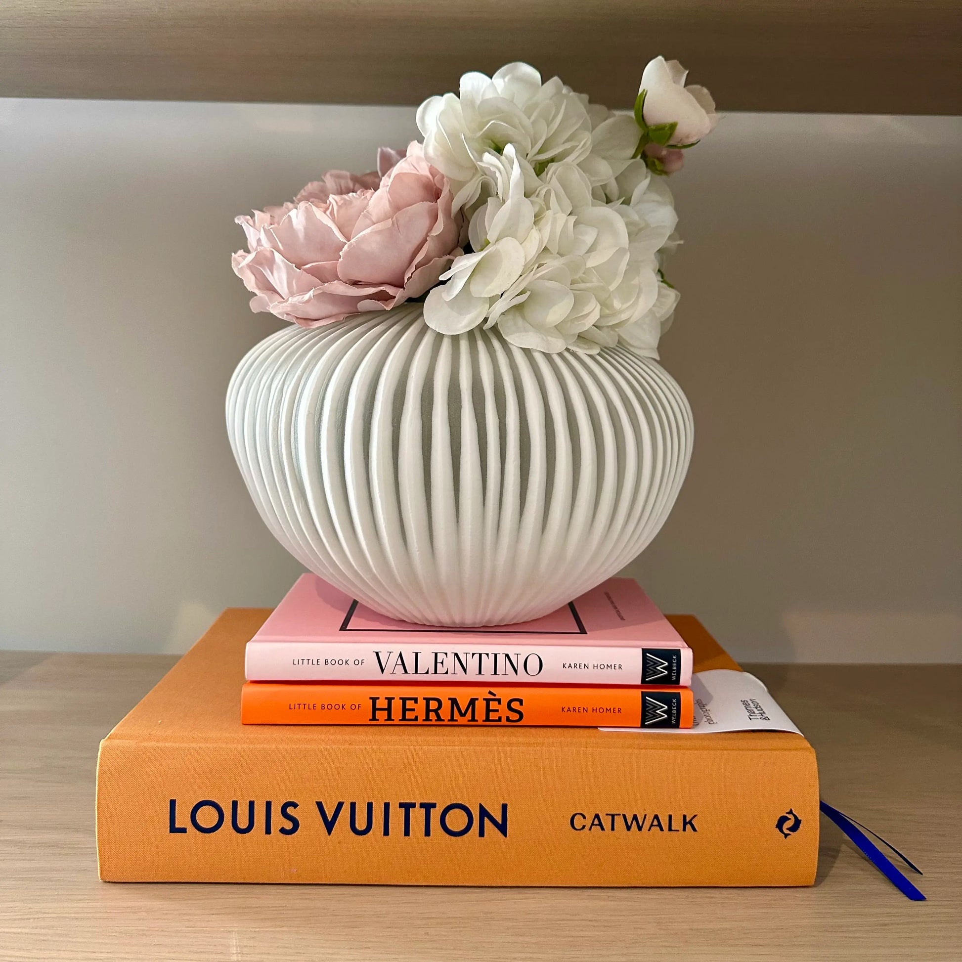 matt-white-ribbed-glass-bowl-vase-on-designer-louis-vuitton-valentino-hermes-books-at-albury-house-interiors