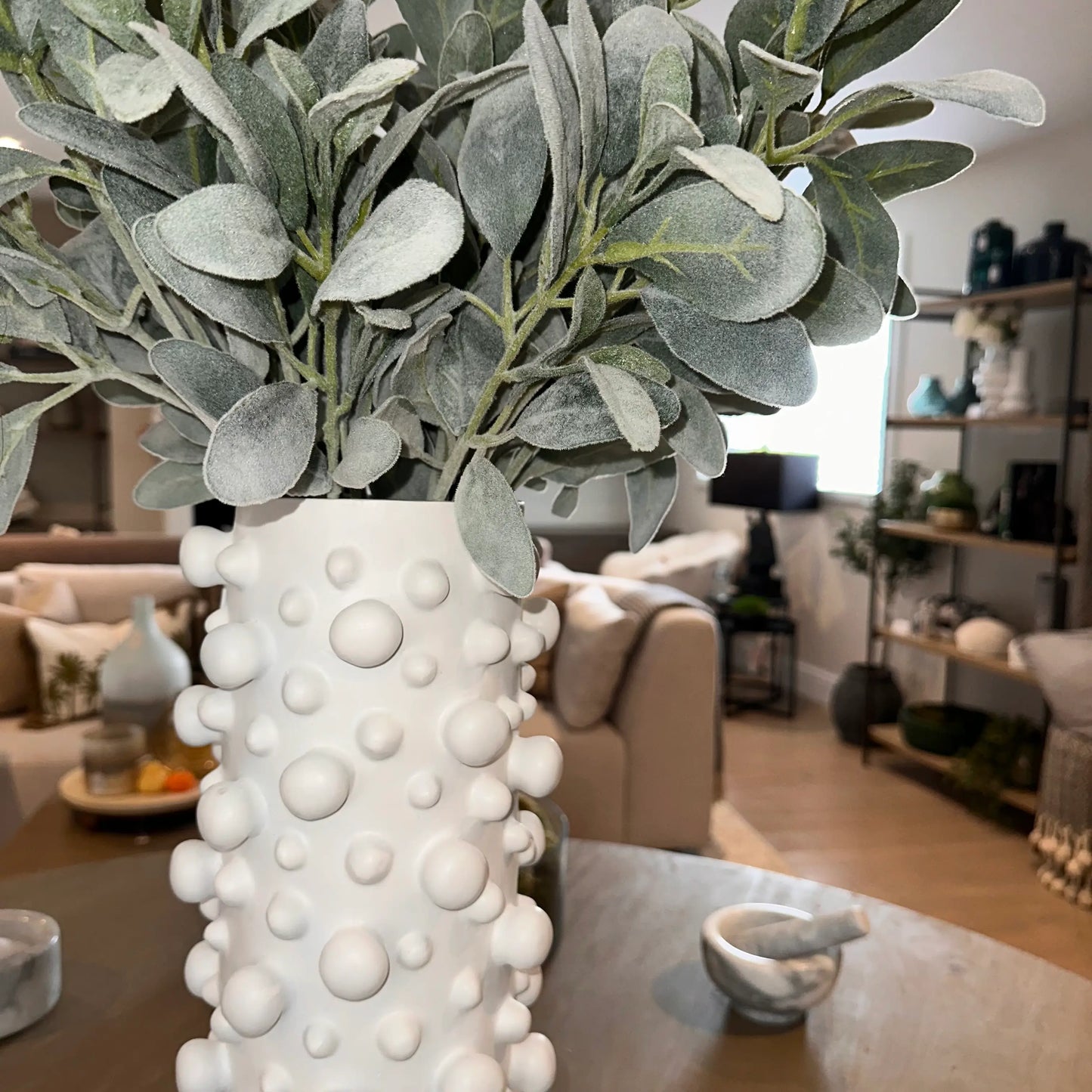 closeup-shot-of-tall-white-polyresin-vase-with-small-and-large-bubbles-and-faux-lambsear-stems-at-albury-house-interiors